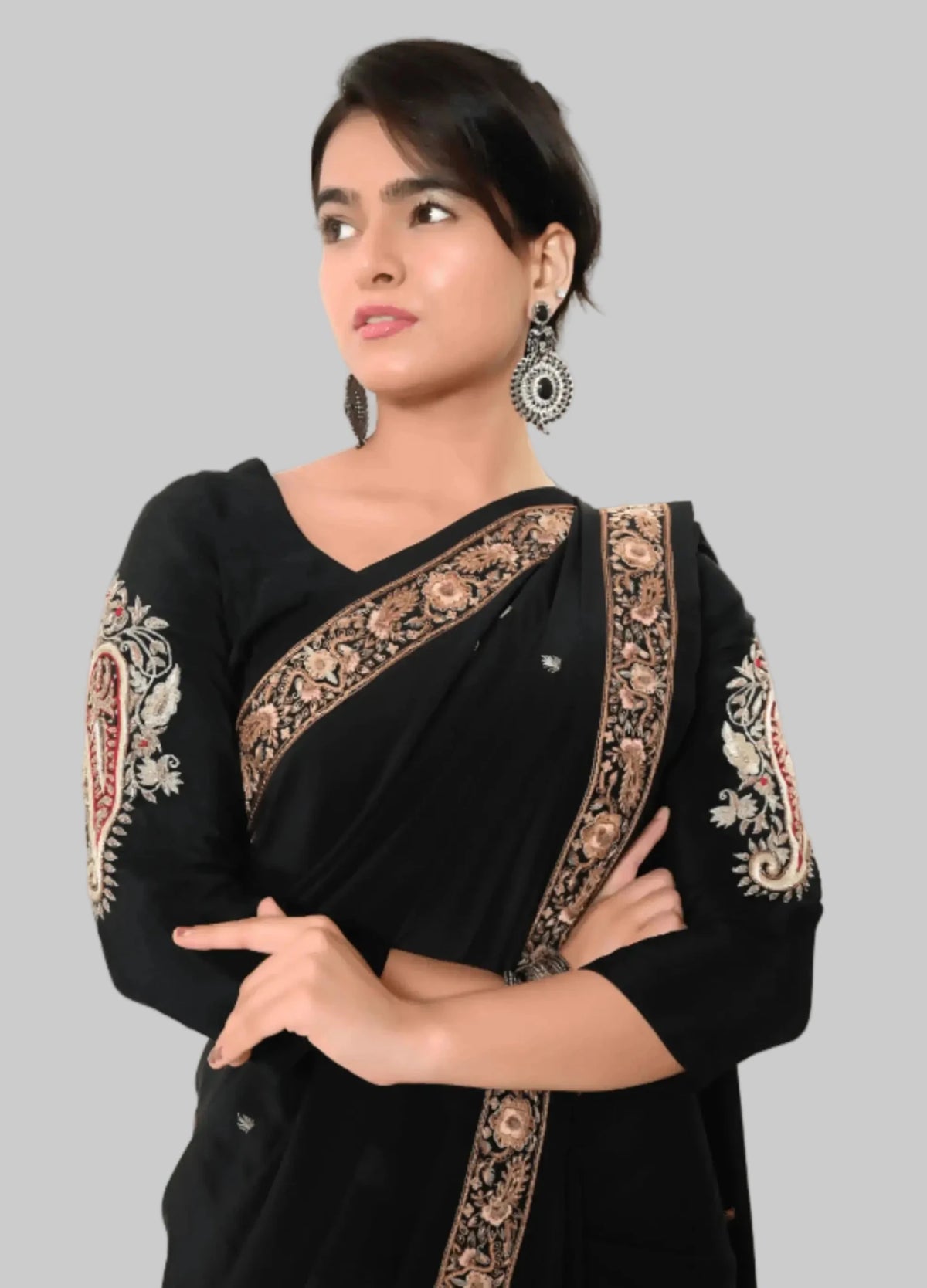 Woman wearing a black saree with intricate gold embroidery on a white background